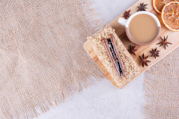 Cup of coffee, cake and orange slices on wooden board