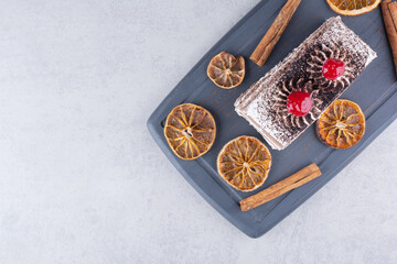 Delicious cake with cinnamons and orange slices on dark plate