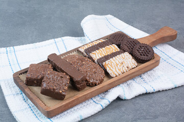A wooden cutting board full of cookies and chocolates