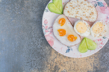 Breakfast plate with bread and eggs on marble surface
