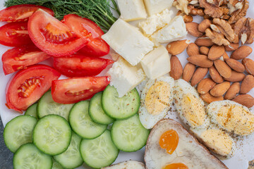 Vegetable slices, eggs, cheese and nuts on white surface