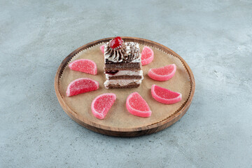 Slice of chocolate cake with marmalades on wooden piece
