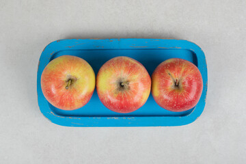Whole red apples on blue plate