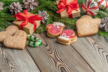 festive christmas and new year background with copy space, fir branches, сhristmas decorations, pine cones, gingerbread cookies and gifts on a vintage wooden table