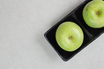 Fresh green apples on black plate