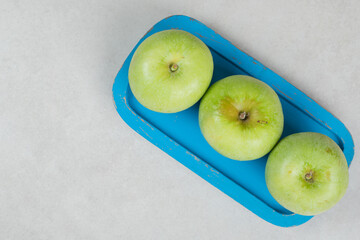 Fresh green apples on blue plate