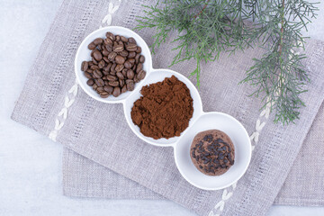 Chocolate cookies, cacao and coffee beans in white bowls