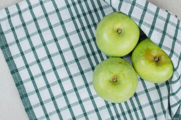 Whole green apples on striped tablecloth