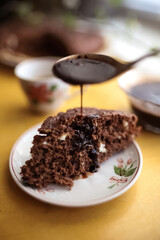 Closeup of hot chocolate is poured from a spoon onto a chocolate biscuit