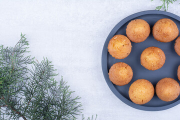 Tasty small cakes on plate with pine branch