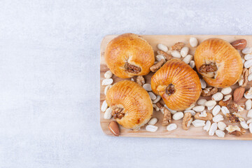 Sweet pastries with kernels on wooden board with various nuts