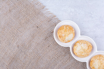 Yummy cookies in white bowls with burlap