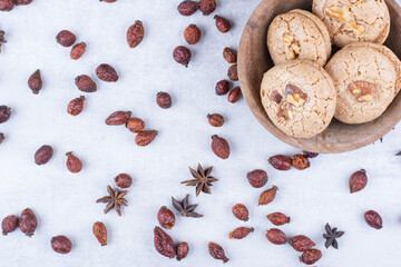 Delicious walnut cookies in bowl with rosehips