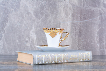 A little cup standing on book on marble background