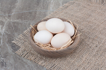 A lot of fresh chicken white eggs on wooden bowl