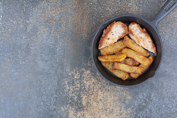 Roasted chicken and potatoes on black pan