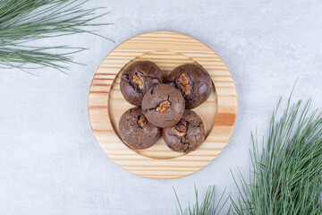 Chocolate cookies with walnut kernels on wooden plate