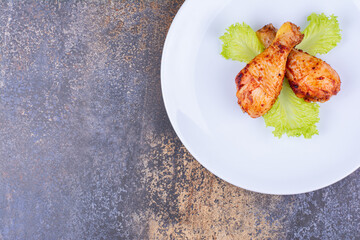 Grilled chicken drumsticks on plate with lettuce