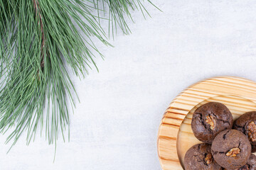 Chocolate cookies with walnut kernels on wooden plate