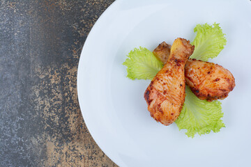 Grilled chicken drumsticks on plate with lettuce