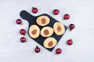 Cookie with jam on black board with glittery balls