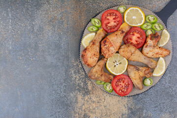 Roasted chicken legs and wings on board with vegetables