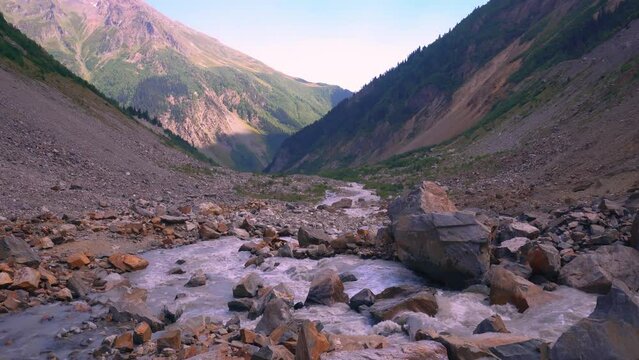 a picture of landscape with river passing through rocky mountains and forest on sunny day. beautiful spring scenery of countryside. Turbulent mountain river among mountains of rocky shore.