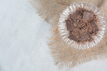 Chocolate bar pieces on glass plate with burlap