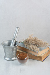Ground coffee, books and mortar and pestle on gray table