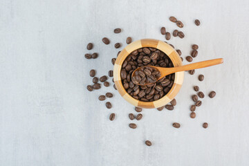 Bunch of coffee beans in wooden bowl with spoon