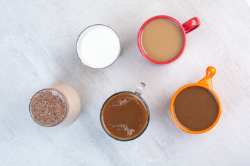 Various delicious coffee cups and milk on gray background