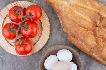 Fresh tomatoes with eggs and bread on marble background