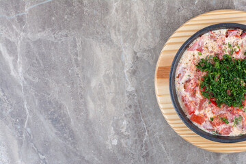 Tasty fried eggs with tomato on dark pan with greens