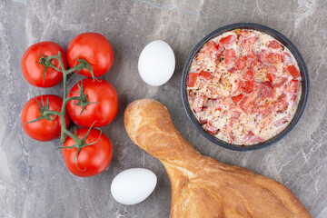 Fresh tomatoes with fried eggs and bread on marble background