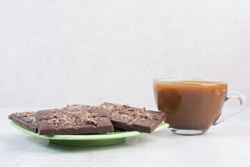 Cup of coffee and chocolate bar on gray background