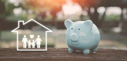 Saving money for home concep, charity, family finance plan concept, fundraising,blue piggy bank and icon family in home on table, investment, financial crisis concept.home lone concept