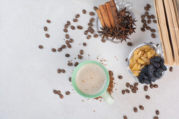 A cup of coffee with dried oranges and nuts on marble background