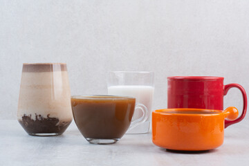 Various delicious coffee cups and milk on gray background