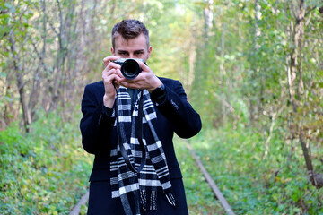 Photographer in a black coat and scarf with a camera at work. Guy takes pictures on the camera. The photographer guy in a coat and scarf shoots at the camera.