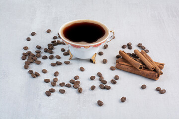 Cup of coffee with coffee beans and cinnamon sticks