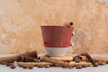 A cup of hot coffee with star anise and cinnamon sticks on crackers