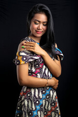 smiling young Asian woman wearing batik clothes isolated on black background. Batik Day.