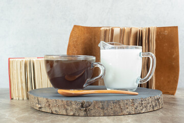 Obraz na płótnie Canvas Cup of coffee, spoon and milk on wood piece