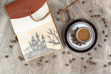 Coffee cup, beans and notebook on marble background