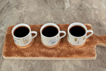 Three cups of espresso on wooden board