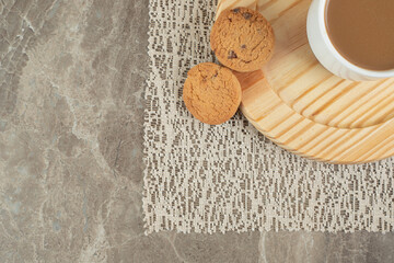 Cup of coffee and biscuits on wooden plate