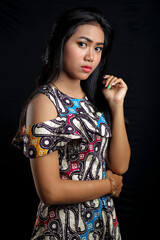 Beautiful young asian woman wearing batik isolated on black background. Batik Day.