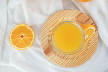 A glass of juice with fresh oranges on wooden plate
