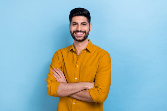 Photo of smart brunet millennial guy crossed arms wear yellow shirt isolated on blue color background