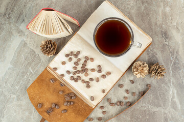 Cup of espresso and coffee beans on open notebook